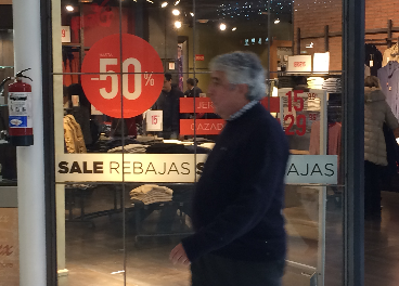 Hombre pasando delante de un cartel de rebajas