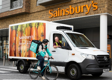 Rider de Deliveroo junto a camión de Sainsbury