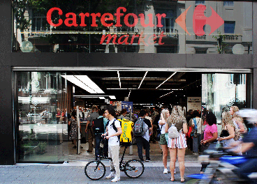 Rider de Glovo ante una tienda de Carrefour